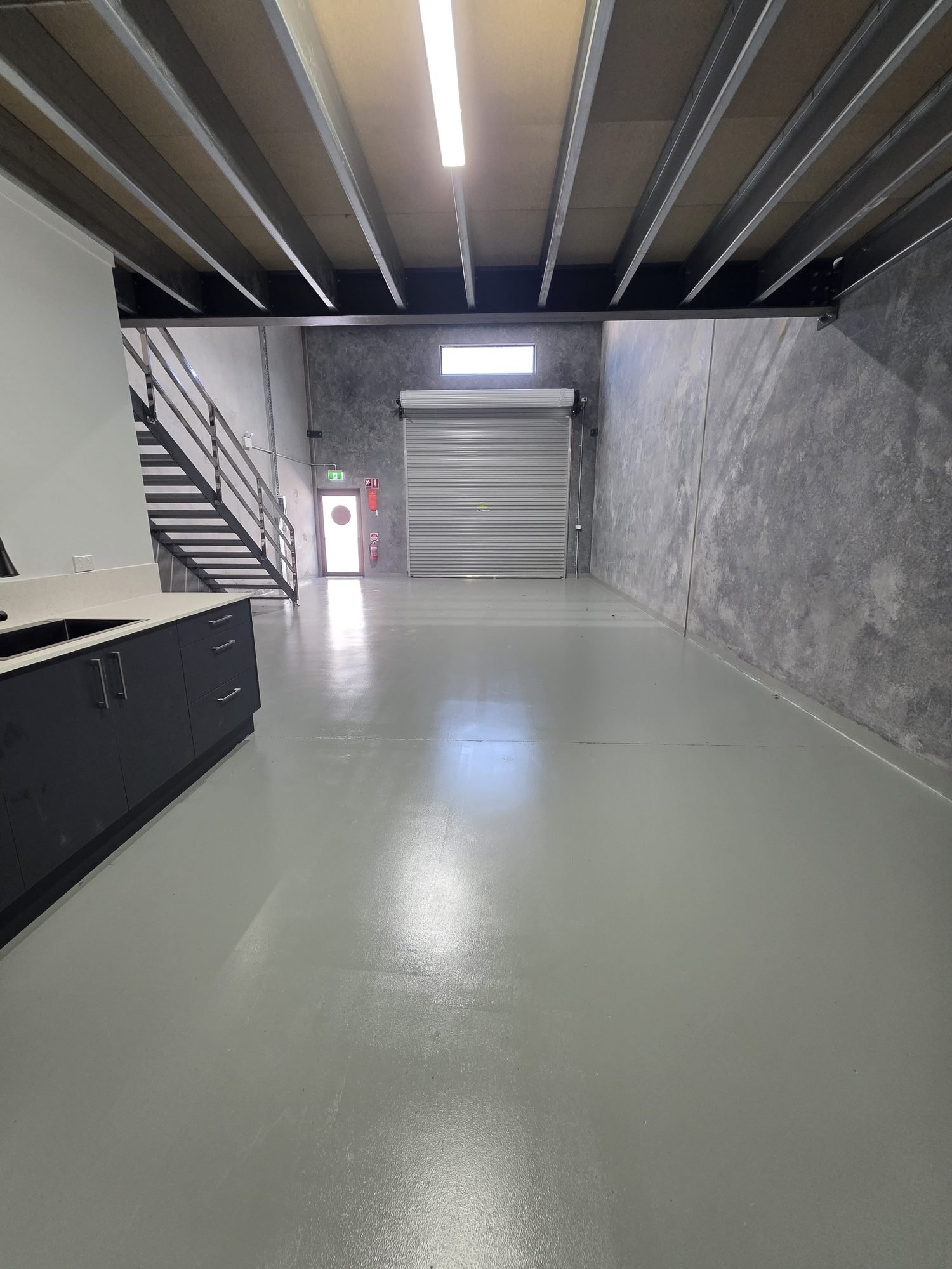 Completed factory unit interior at Pacific Woods Estate — mezzanine, kitchenette and roller door, Townsend NSW